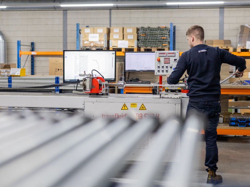 Heuver Hydrauliek medewerker buigt hydraulische leidingen op maat met CNC buigmachine in de werkplaats.
