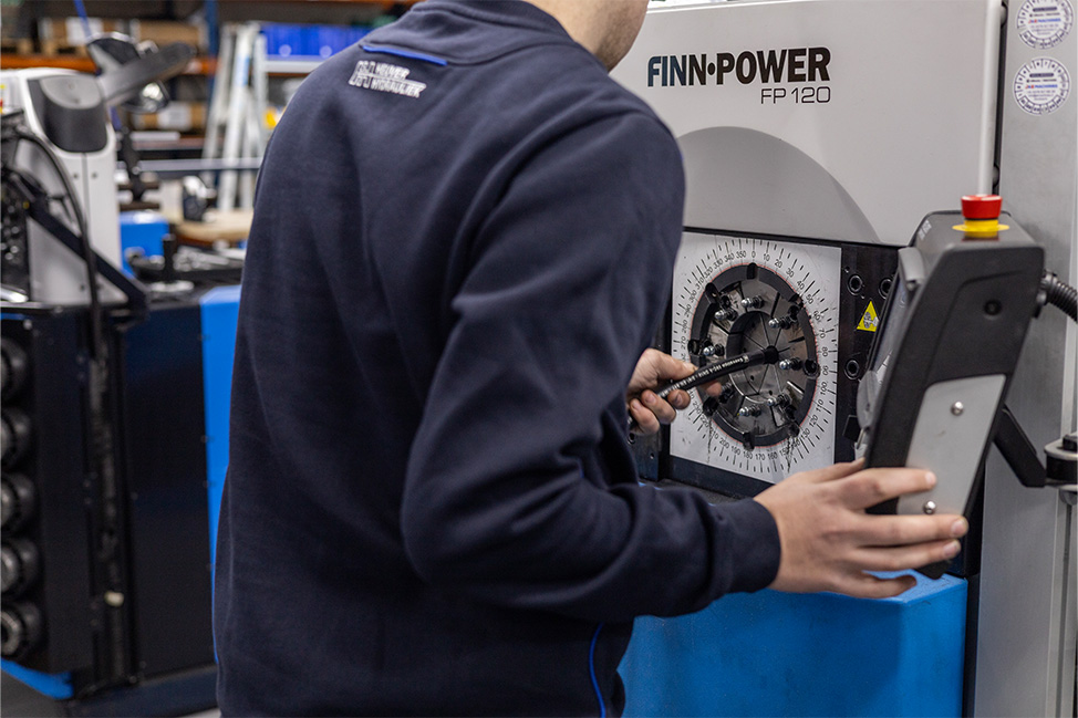 Monteur van Heuver Hydrauliek assembleert hogedrukslang met persmachine in de werkplaats