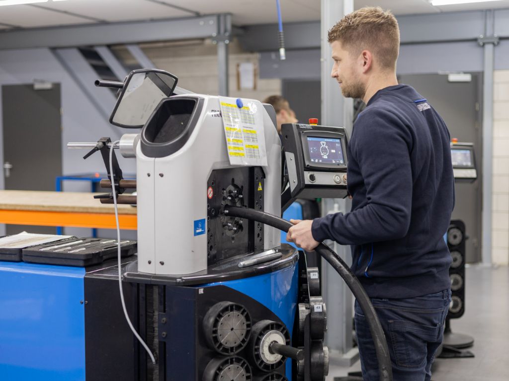 Monteur perst hydrauliek slangen op maat met slangenpers in werkplaats