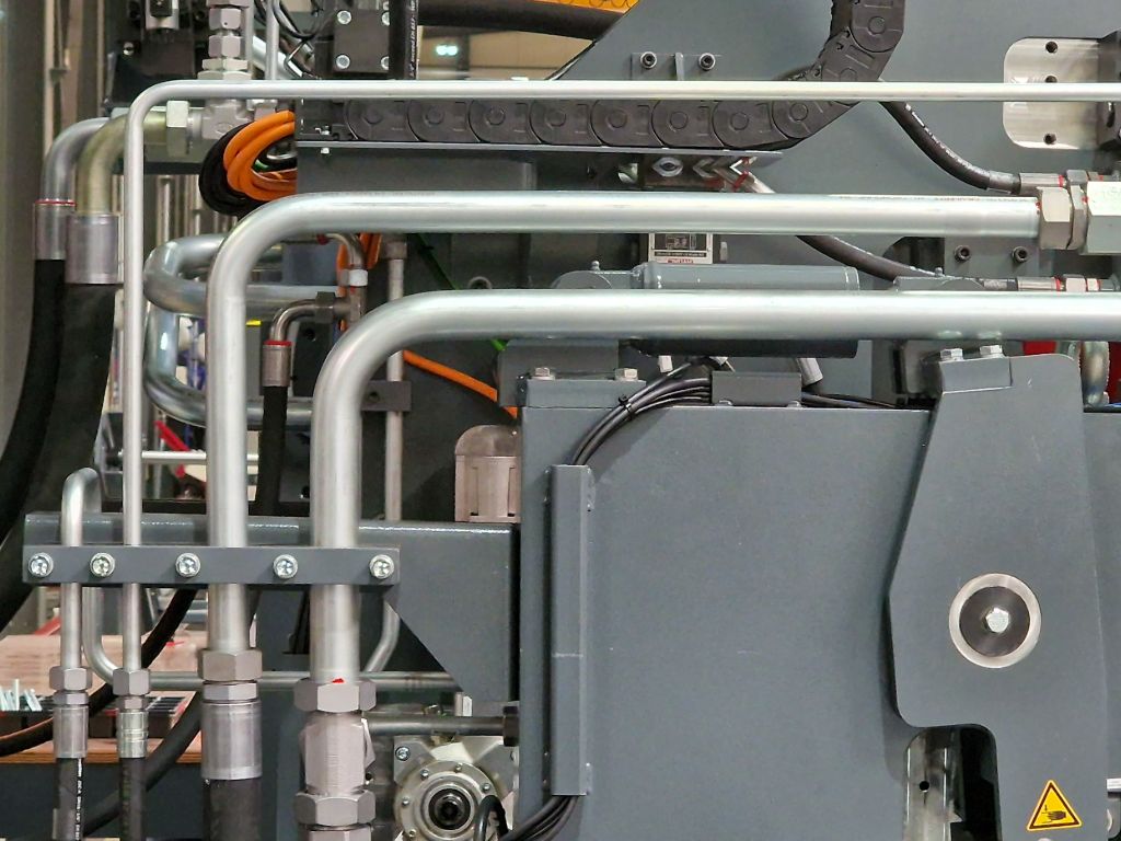 Hydraulische leidingenset met stalen buizen en koppelingen op industriële machine, gemonteerd door Heuver Hydrauliek.
