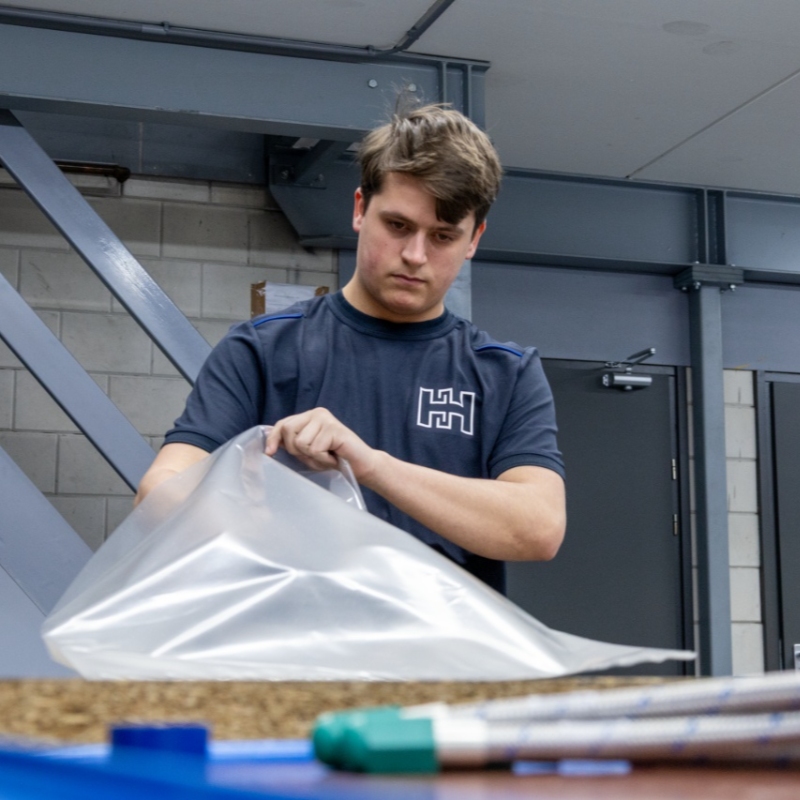Heuver Hydrauliek medewerker verpakt hydraulische onderdelen met beschermfolie voor veilige verzending.